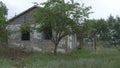 An old, abandoned house in the village, on a background of trees. Abandoned house near Donetsk. Destroyed houses and