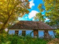 Old abandoned hut in the woods. Tall green trees, old roof, wooden doors and windows Royalty Free Stock Photo