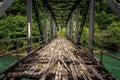 Old abandoned iron bridge spans over green river Royalty Free Stock Photo