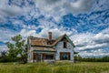 Old, abandoned prairie farmhouse with trees, grass and blue sky in Saskatchewan, Canada Royalty Free Stock Photo