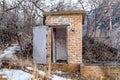 Old abandoned public restroom in the mountain surrounded by leafless brown trees Royalty Free Stock Photo