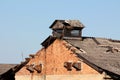 Old abandoned red brick industrial storage warehouse with destroyed wooden roof and rusted venting exhaust fans