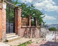 Old abandoned red bricks fence, wrought iron door and green trees on sunny summer day, Balat district, Istanbul, Turkey