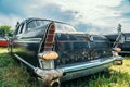 Old abandoned rusty car rusting on green grass