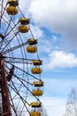 Old abandoned rusty metal radioactive yellow ferris wheel against dramatic sky in amusement park in ghost town Pripyat, Chernobyl Royalty Free Stock Photo