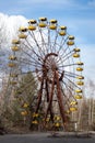 Old abandoned rusty metal radioactive yellow ferris wheel against dramatic sky in amusement park in ghost town Pripyat, Chernobyl Royalty Free Stock Photo