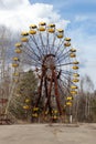 Old abandoned rusty metal radioactive yellow ferris wheel against dramatic sky in amusement park in ghost town Pripyat, Chernobyl Royalty Free Stock Photo