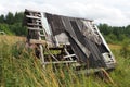 Old abandoned sad well or house in Nyrki village, Karelia. A lopsided wooden roof with slipped roofing material. A field Royalty Free Stock Photo