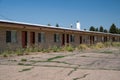 Old, abandoned seedy motorcourt style motel, decays in the sun. Weeds overgrowing in the parking lot