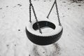 Old abandoned set of tire swings covered by snow against winter forest landscape background. Childhood memories concept. Royalty Free Stock Photo