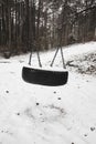 Old abandoned set of tire swings covered by snow against winter forest landscape background. Childhood memories concept. Royalty Free Stock Photo