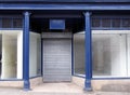 Old Abandoned Shop Painted Blue And White With Empty Store Front Dirty Windows And Closed Shutters On The Door