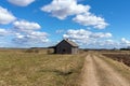 An old abandoned small wooden house in the field blue sky white clouds, barn or scary concept Royalty Free Stock Photo
