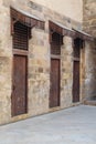 Old abandoned stone bricks wall with three weathered wooden doors covered with wooden grid Royalty Free Stock Photo