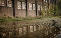 Old abandoned stone building with broken windows and a puddle outside