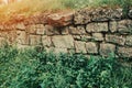 An old abandoned stone wall made of old stones overgrown with grass and moss Royalty Free Stock Photo