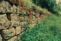 An old abandoned stone wall made of old stones overgrown with grass and moss Royalty Free Stock Photo