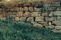 An old abandoned stone wall made of old stones overgrown with grass and moss Royalty Free Stock Photo