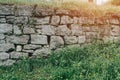 An old abandoned stone wall made of old stones overgrown with grass and moss Royalty Free Stock Photo