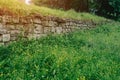 An old abandoned stone wall made of old stones overgrown with grass and moss Royalty Free Stock Photo