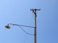 Old abandoned street light with broken wires under blue sky