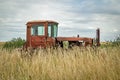 An old abandoned tractor in a field overgrown with tall grass Royalty Free Stock Photo