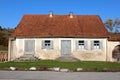 Old abandoned traditional family house with dilapidated facade and wooden window blinds surrounded with grass and clear blue sky Royalty Free Stock Photo