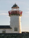 Old abandoned white lighthouse building against a sky background. Nobody. Empty tower with red metal railing