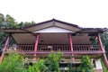 Old, abandoned wood two floors level house in disrepair green trees and vines cover it. Royalty Free Stock Photo