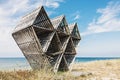 Abandoned wooden geometric sculpture on wild beach