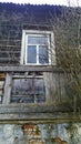 Old abandoned wooden house with window and dry tree branches in disrepair. Dirty broken building background. Poverty. Economic and Royalty Free Stock Photo