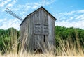 Old abandoned wooden mill and wheat summer field Royalty Free Stock Photo