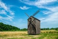 Old abandoned wooden mill and wheat summer field Royalty Free Stock Photo