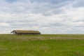 Old abandoned wooden structure in an open field on a cloudy day