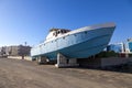 Old abandoned wrecked speed boat at ship or boat graveyard. Lots of different dry docked, destroyed, weathered, old, abandoned boa