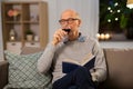 Senior man with book drinking red wine at home Royalty Free Stock Photo