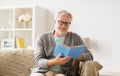 Senior man on sofa reading book at home Royalty Free Stock Photo