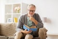 Senior man on sofa reading book at home Royalty Free Stock Photo