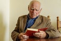 Old age, leisure and people concept - senior man sitting on sofa and reading book at home. Slavic appearance. Elderly Royalty Free Stock Photo