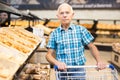 Elderly man buying bread and pastries in grocery section of the supermarket Royalty Free Stock Photo