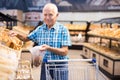 Elderly man buying bread and pastries in grocery section of the supermarket Royalty Free Stock Photo