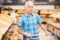 Old age senor examines bakery products in the grocery section of the supermarket Royalty Free Stock Photo