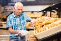 Old age senor examines bakery products in the grocery section of the supermarket Royalty Free Stock Photo