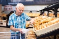 Old age senor examines bakery products in the grocery section of the supermarket Royalty Free Stock Photo