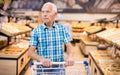 Old age senor examines bakery products in the grocery section of the supermarket Royalty Free Stock Photo