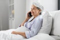 senior woman calling on smartphone in bed at home Royalty Free Stock Photo