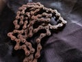 Old, aged, broken, and weathered motorbike chain on black fabric background