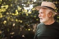 Old aged man standing in profile against background of trees