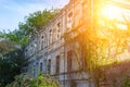 Old aged ruined abandoned two-storied brick building facade with brocken glass windows overgrown by green ivy. mystical