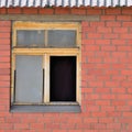 Old aged shed broken window glass, red bricks hut wall background, weathered grungy rusty dirty damaged wooden frame, textured Royalty Free Stock Photo